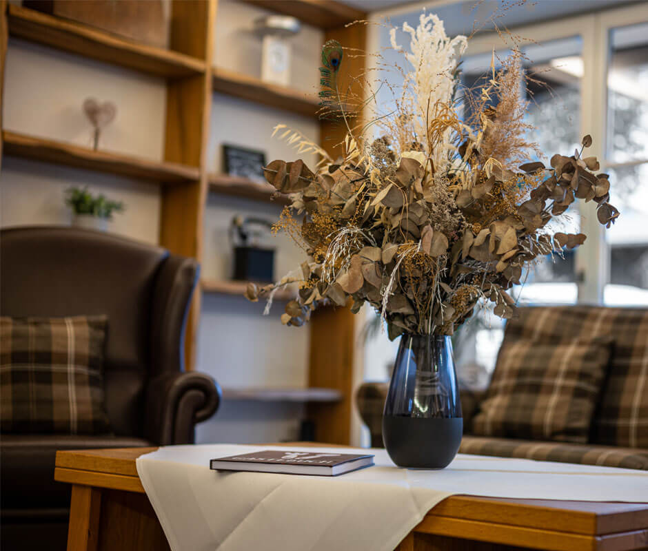 Zwei Polstermöbel mit einem kleinen Tisch auf dem ein Gesteck aus Trockenblumen steht